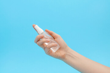 Alcohol sanitizer in a female hand on a blue background.