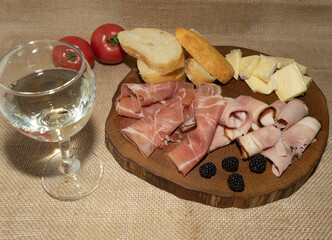Wine appetizer. Ham, Parma ham, baguette, Cheese on a wooden stand.