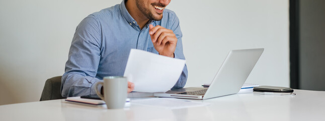 Banner panorama close up mid section body of young smiling cheerful successful businessman entrepreneur in modern bright office on video conference call or chat working from home - Powered by Adobe