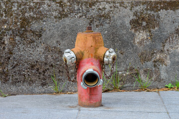 old red and yellow hydrant against a gray wall