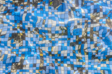 old damaged small tiles on the bottom of the swimming pool, top view through the water, background,...