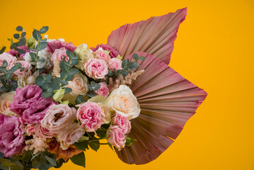 beautiful composition of roses and palm leaves on a yellow background