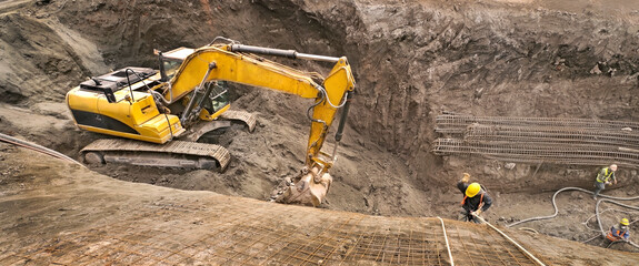 Panoramic view of an excavator vehicle in construction site among an abseil worker.
Excavation site...