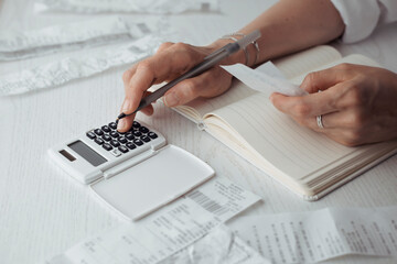 A woman counts the paid bills on the calculator. Home accounting. Woman manage paper bill to be paid. Expense calculation to control money saving.