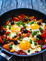 Shakshuka - fried eggs with sausages and vegetables in frying pan