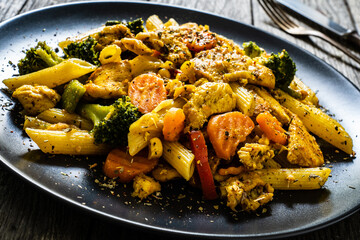 Chicken ragout with penne on wooden table
