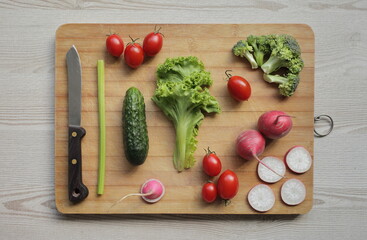 Fresh vegetables on a cutting board on a light wooden table