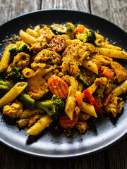 Chicken ragout with penne on wooden table
