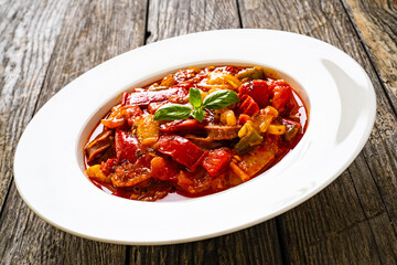 Delicious stew - vegetable with sausages on wooden table