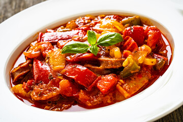 Delicious stew - vegetable with sausages on wooden table