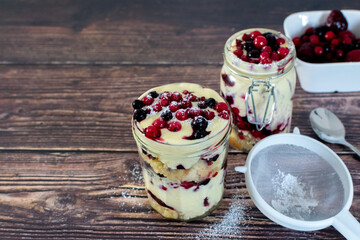 red berry trifle in a mason jar with icing sugar and fruit 