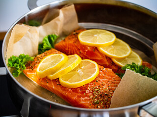 Raw salmon steaks with lemon and parsley in pot
