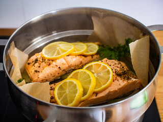 Steamed salmon steaks with lemon and parsley in pot
