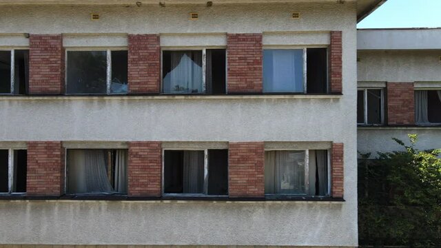 Wide Angle Aerial of exterior scary abandoned building with broken old window with curtains, chernobyl concept, facade of an old building
