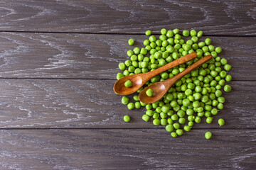 ripe sweet peeled green peas on a wooden background top view. background with sweet green peas. peas in wooden spoons. green peas and a copy of space.