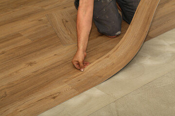 The worker installing new vinyl tile floor