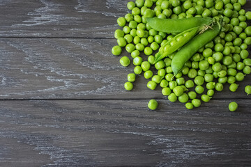 peeled sweet peas and pea pods on a wooden background top view. background with sweet green pea pods.