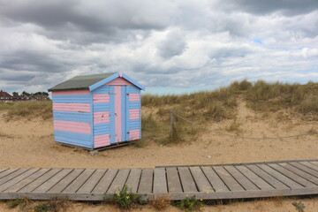 Obraz na płótnie Canvas Great Yarmouth, beach cabins, summer day, traditional UK cabin, English East Coast, sky with clouds, no people, large stretch of sand, north sea