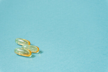 Close-up of several capsules omega-3 on blue-green background.