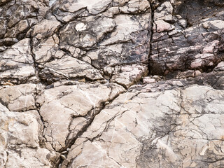 Weathered rock textured background. Rough cracked surface of natural stone.