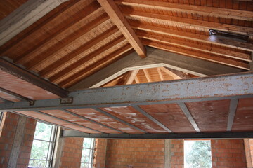 ceiling of a house under construction with red brick and exposed beams