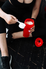 A girl after a workout holds a shaker with protein. Sports nutrition