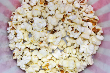 Scattered popcorn, close up inside a plastic bucket.