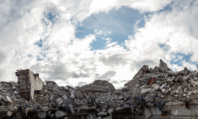 A pile of concrete gray debris of a destroyed building with a huge beam in the foreground against a...