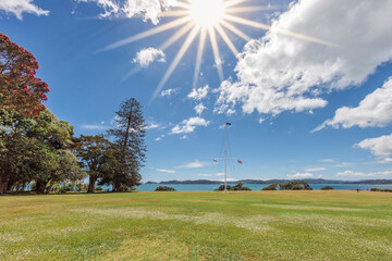 Fototapeta na wymiar Waitangi Treaty Grounds with sun and flagstaff in Bay of Islands, New Zealand