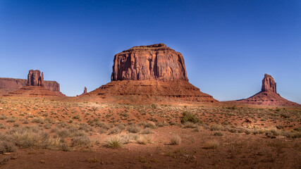 The towering red sandstone formations of West Mitten Butte, Merrick Butte, East Mitten Buttes in  Monument Valley Navajo Tribal Park desert landscape on the border of Arizona and Utah, United States