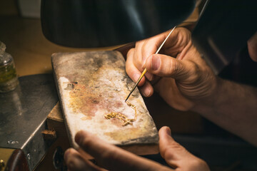 Fototapeta na wymiar Hands of a craftsman jeweler working on jewelry. Goldsmith. Goldsmith workshop jewels and articles of work value