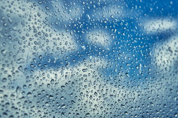 The rain drops at the window surface on blue sky background 