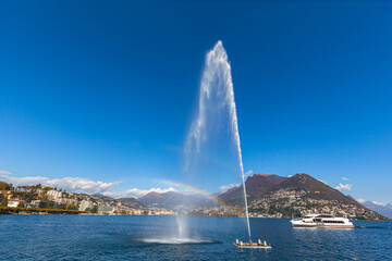 Naklejka na ściany i meble Panorama view of Lugano Lake and city with fountain and rainbow