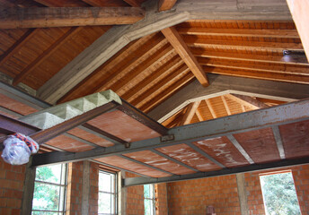 ceiling of a house under construction with red brick and exposed beams