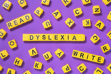 Dyslexia, read write words yellow on pink purple with scattered letters cubes around, reading difficulty and disorder visual and auditory memory or test concept. Education neurology with copy space - obrazy, fototapety, plakaty