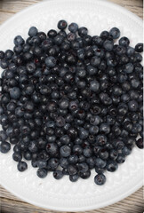 Top view of a white plate with blueberries. Vertical arrangement