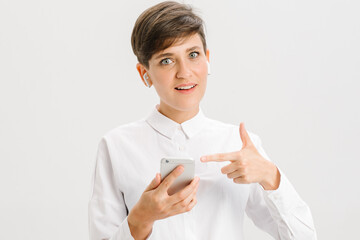  smiling woman uses wireless headphones for a video call and showing like. white background in studio. online business meeting concept.