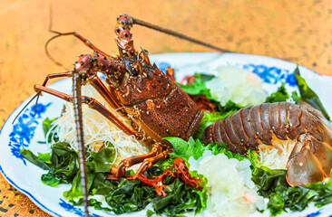 Close-up on raw sashimi high-class japanese cuisine of fresh Ise-ebi spiny lobster in a dish plate with green algae, shiso leaves and a julienne of radish daikon sengiri.