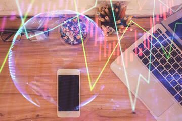 Double exposure of financial graph hologram over desktop with phone. Top view. Mobile trade...