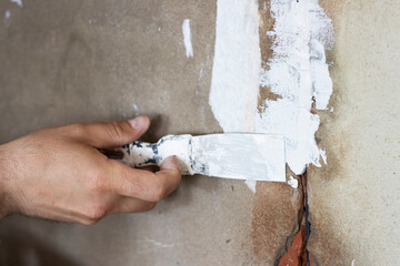 a hand puts putty paste on the wall. sealing of walls
