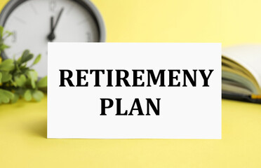 retiremeny plan text NAPILAN on a white sheet of paper on a yellow background near a notepad and an alarm clock