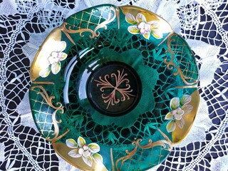 Beautiful green vintage glass bowl with flowers on a lace napkin on a black wooden table