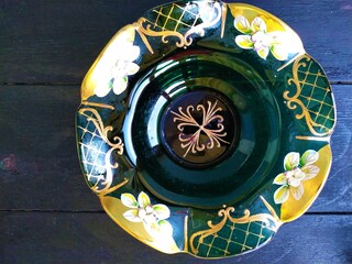 Beautiful green vintage glass bowl with flowers on a lace napkin on a black wooden table