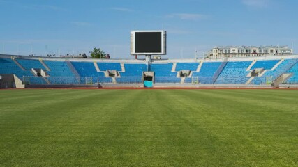 Empty sports stadium with nobody from football field. Travelling in through the grass to big scoreboard. - Powered by Adobe