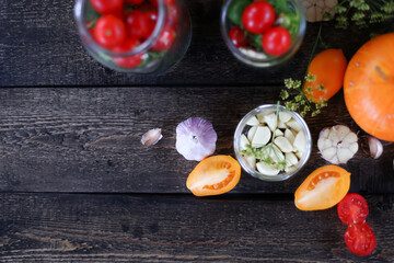 Woman's hands rolls glass preserves with jars sealer. Making homemade vegetables for coronavirus crisis. Tomatoes, pumpkins, garlic, peppers, pickles, zucchini lie on wooden table