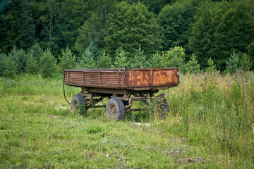 Fototapeta na wymiar Abandoned old cargo trailer stands in a field on green grass