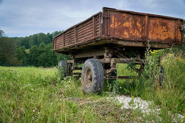 Abandoned old cargo trailer stands in a field on green grass. Close-up