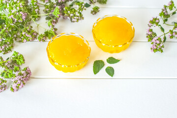 flower honey in transparent glass bowls and fresh oregano flowers on a white background. background with honey and flowers.