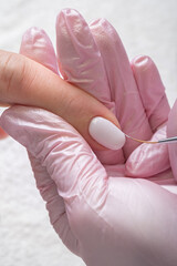 Woman in nail salon receiving manicure by beautician. Manicure process in beauty salon, close up. Close up of a woman hand with white nail polish after the manicure. 