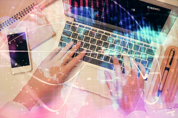 Double exposure of woman hands working on computer and financial theme hologram drawing. Top View. Business concept.